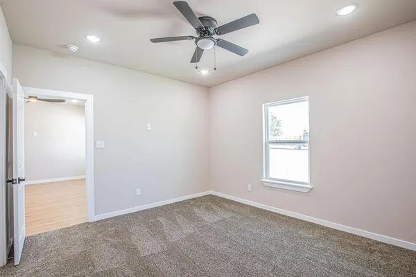 an empty room with a window and a fan