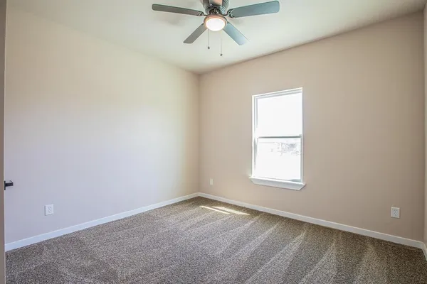 an empty room with a window and a fan