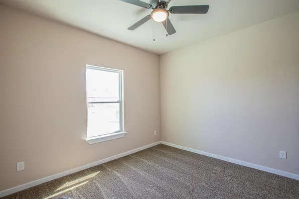 an empty room with a window and a fan