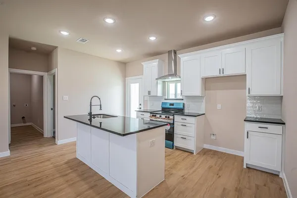 a kitchen with white cabinets appliances and wooden floor