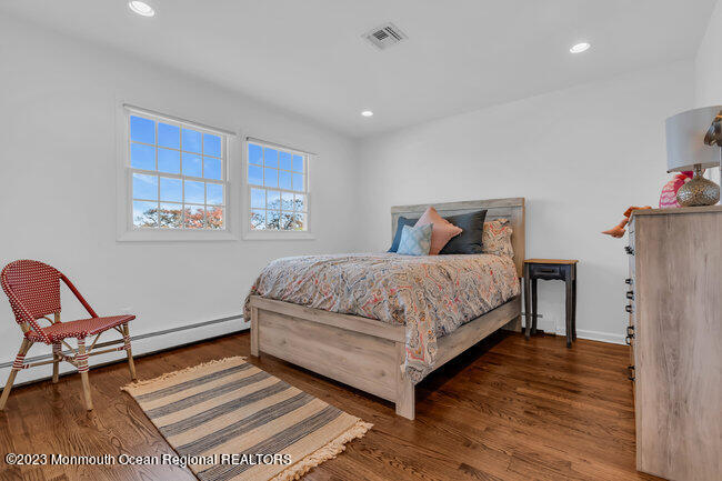 809 Lake Drive Spring Lake, NJ 07762 - Photo 22 of 34 a bedroom with a bed a chair and potted plant on the wooden floor