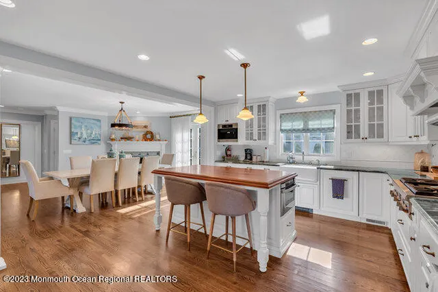 a kitchen with stainless steel appliances kitchen island granite countertop a table chairs sink and wooden cabinets