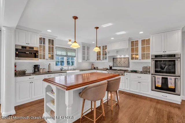 a kitchen with stainless steel appliances granite countertop a stove top oven a sink dishwasher a dining table and chairs with wooden floor