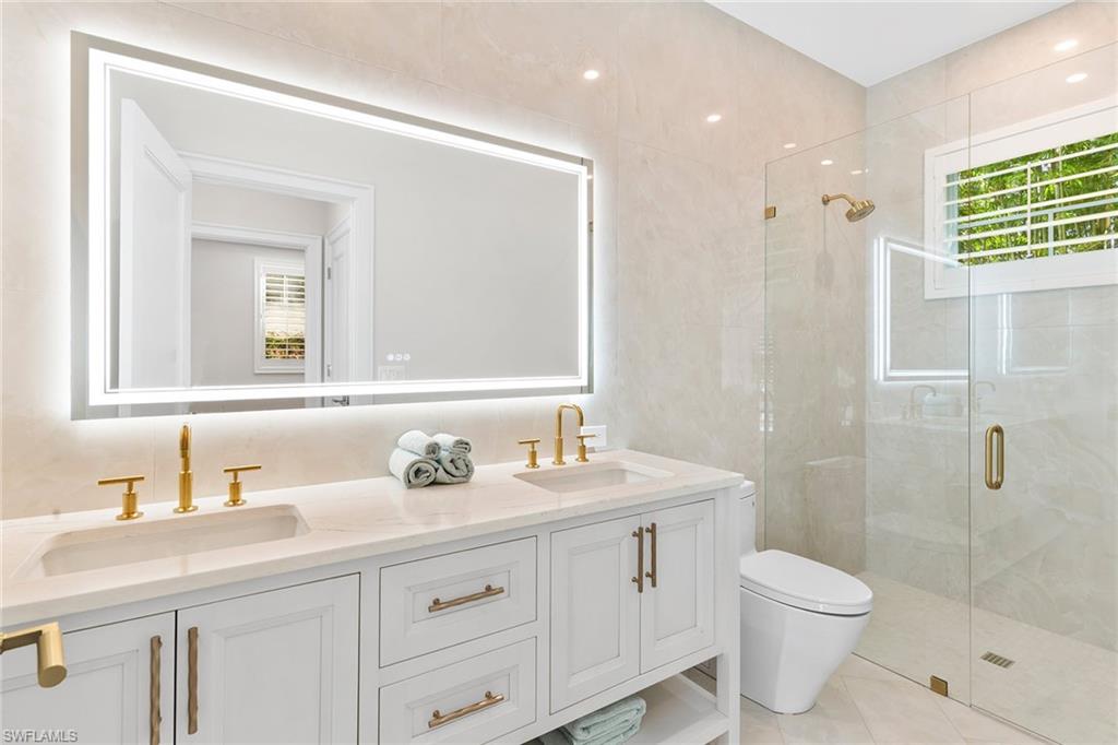 810 9th Street South Naples, FL 34102 - Photo 15 of 32 a bathroom with a toilet a sink a mirror a shower and vanity