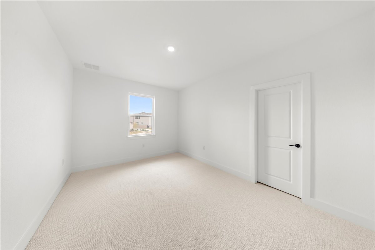 8700 Olmsted Way Austin, TX 78744 - Photo 28 of 40 Empty room with light colored carpet and recessed lighting