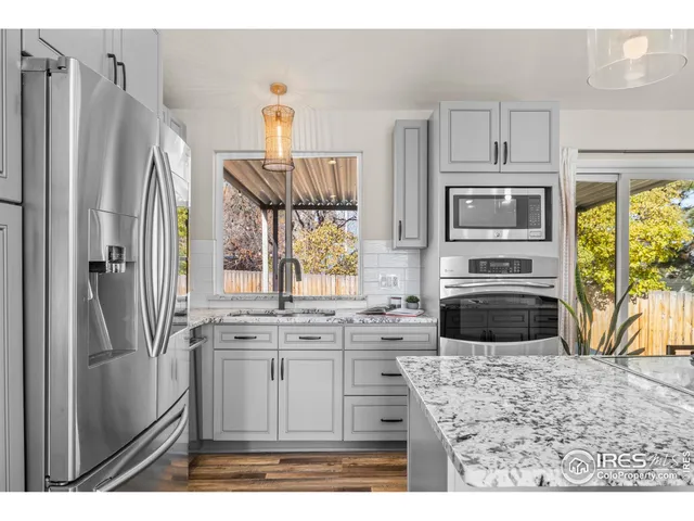 a kitchen with stainless steel appliances granite countertop a refrigerator a stove a sink and a microwave