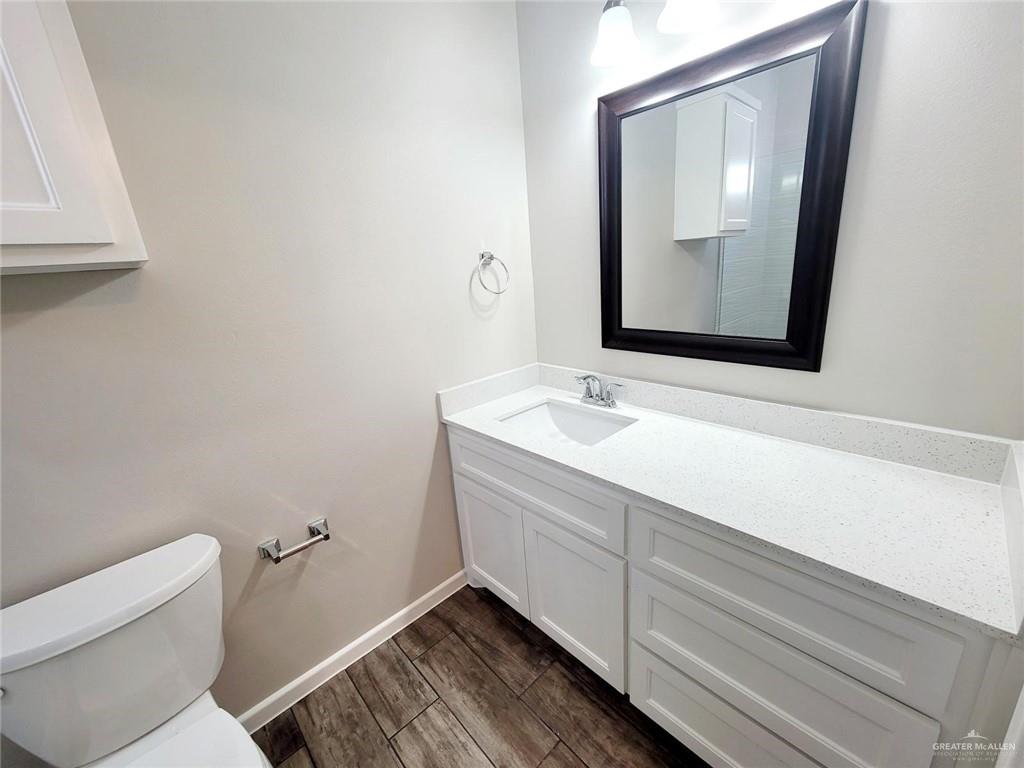 1312 Petri Drive, Unit 2 Weslaco, TX 78596 - Photo 13 of 15 a bathroom with a toilet sink vanity and mirror