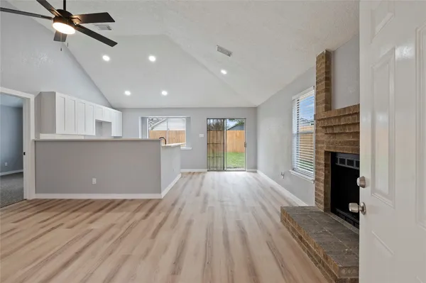 a view of kitchen and hall with wooden floor and fireplace