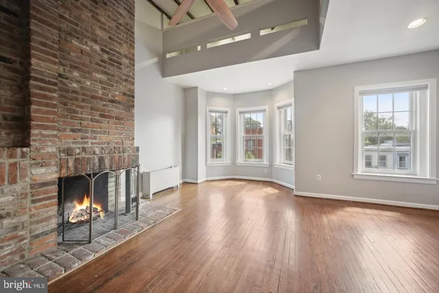an empty room with windows and fireplace
