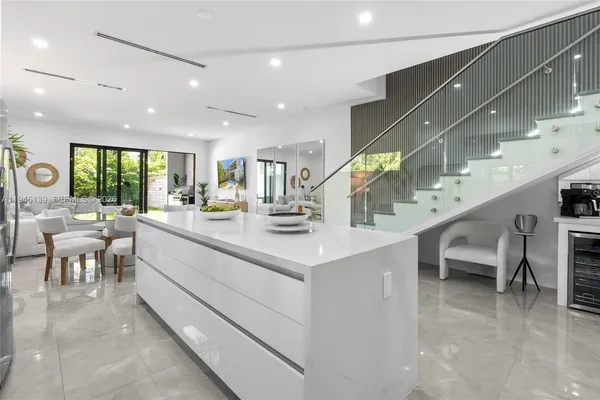 a kitchen with a refrigerator a sink dishwasher a barbeque oven and a dining table with wooden floor
