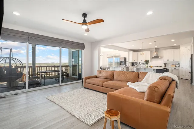 a living room with furniture a ceiling fan and a large window