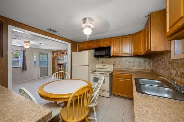 a kitchen with stainless steel appliances granite countertop a sink a stove a refrigerator cabinets and dining table