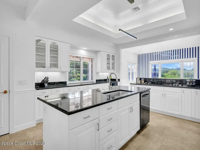 a kitchen with granite countertop white cabinets and sink