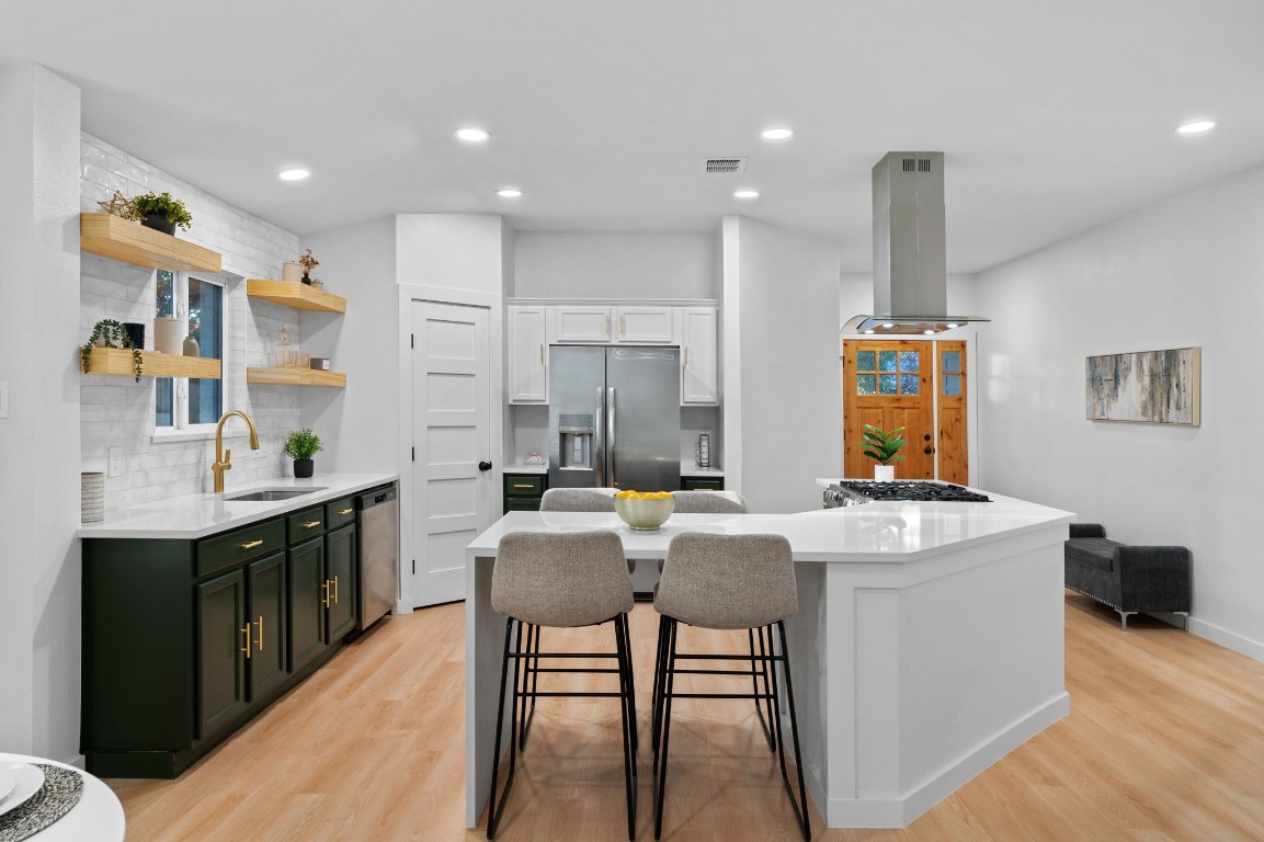 a kitchen with kitchen island stainless steel appliances a table chairs sink and cabinets