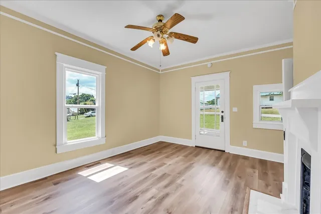 a view of an empty room with window and wooden floor