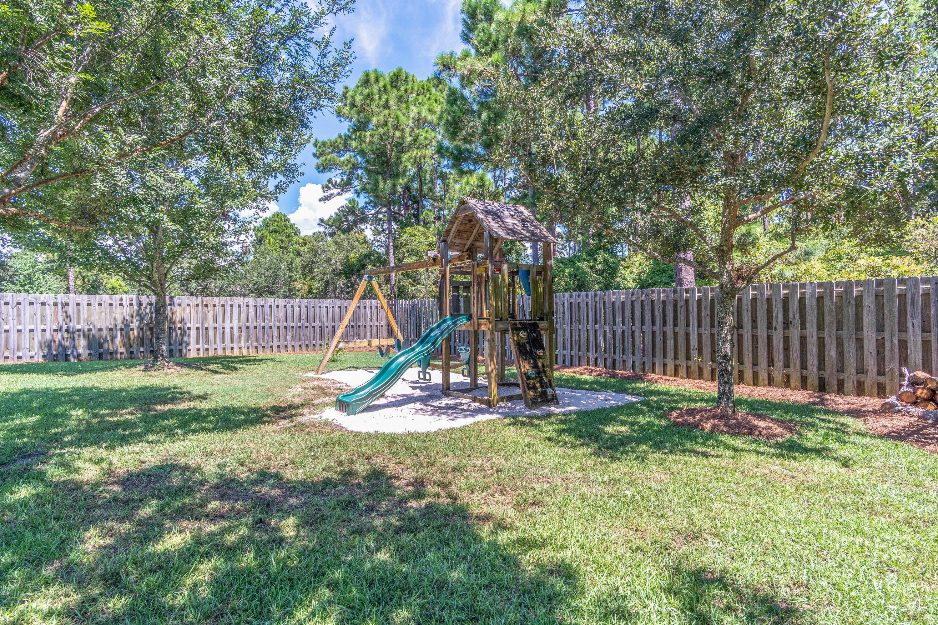 622 East Shipwreck Road Santa Rosa Beach, FL 32459 - Photo 25 of 39 a view of a backyard with a slide trees and wooden fence