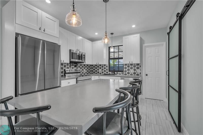 a kitchen with kitchen island a dining table chairs stainless steel appliances and cabinets