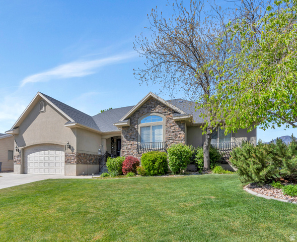 Stucco and stone exterior featuring an arched window, covered entry, and attached garage