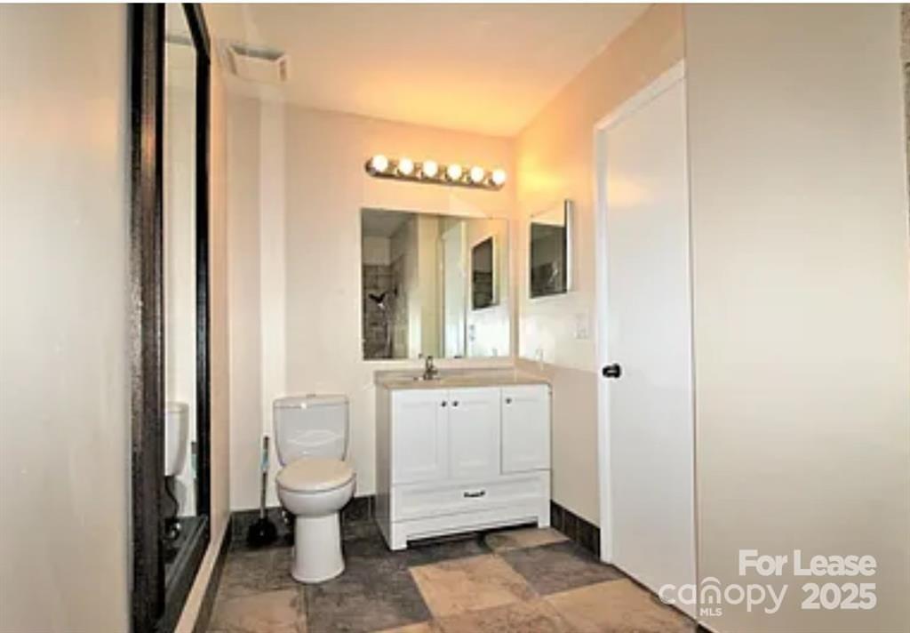 4809 Spring Lake Drive, Unit E Charlotte, NC 28212 - Photo 15 of 18 a spacious bathroom with a toilet sink and mirror