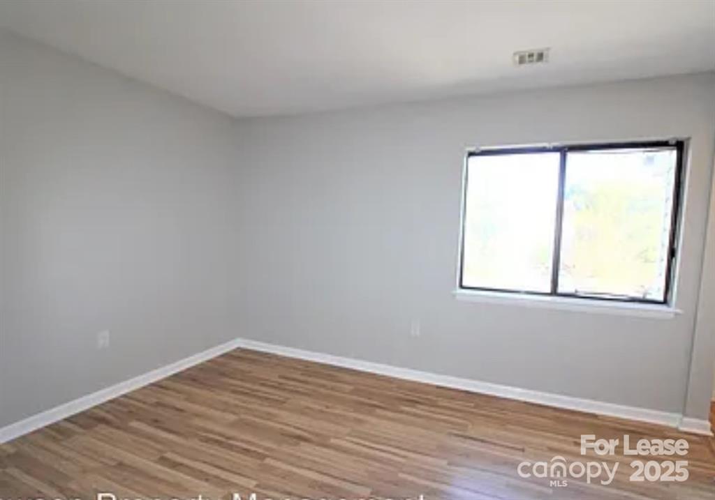 4809 Spring Lake Drive, Unit E Charlotte, NC 28212 - Photo 7 of 18 wooden floor in an empty room with a window