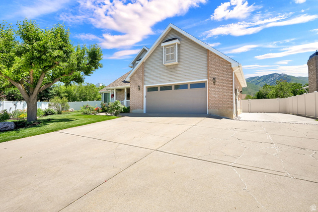 4792 Glasmann Way South Ogden, UT 84403 - Photo 7 of 70 Light brick and siding exterior featuring a multi-car driveway, attached garage, manicured lawn, and mature tree