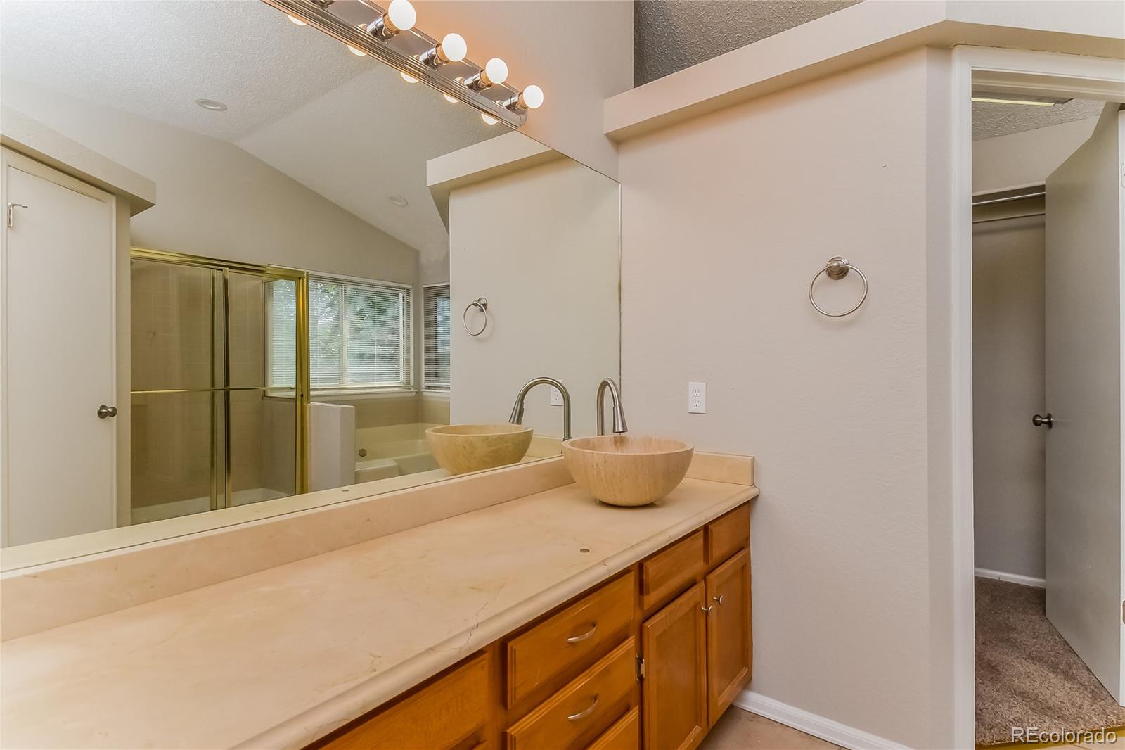 5245 Quasar Court Colorado Springs, CO 80917 - Photo 14 of 18 a bathroom with a double vanity sink a mirror and a shower