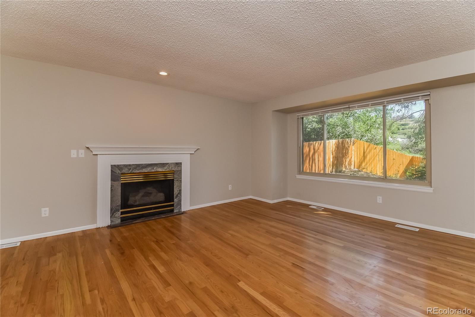 5245 Quasar Court Colorado Springs, CO 80917 - Photo 2 of 18 a view of empty room with wooden floor and fireplace