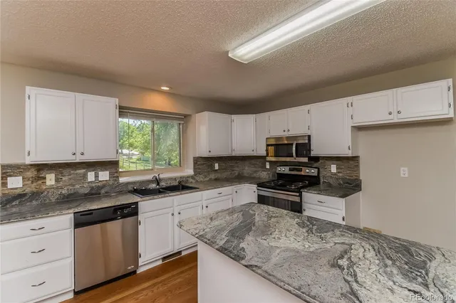 a kitchen with granite countertop a sink stove and cabinets