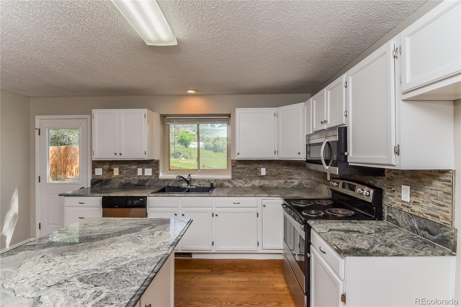 5245 Quasar Court Colorado Springs, CO 80917 - Photo 7 of 18 a kitchen with granite countertop a stove sink and cabinets