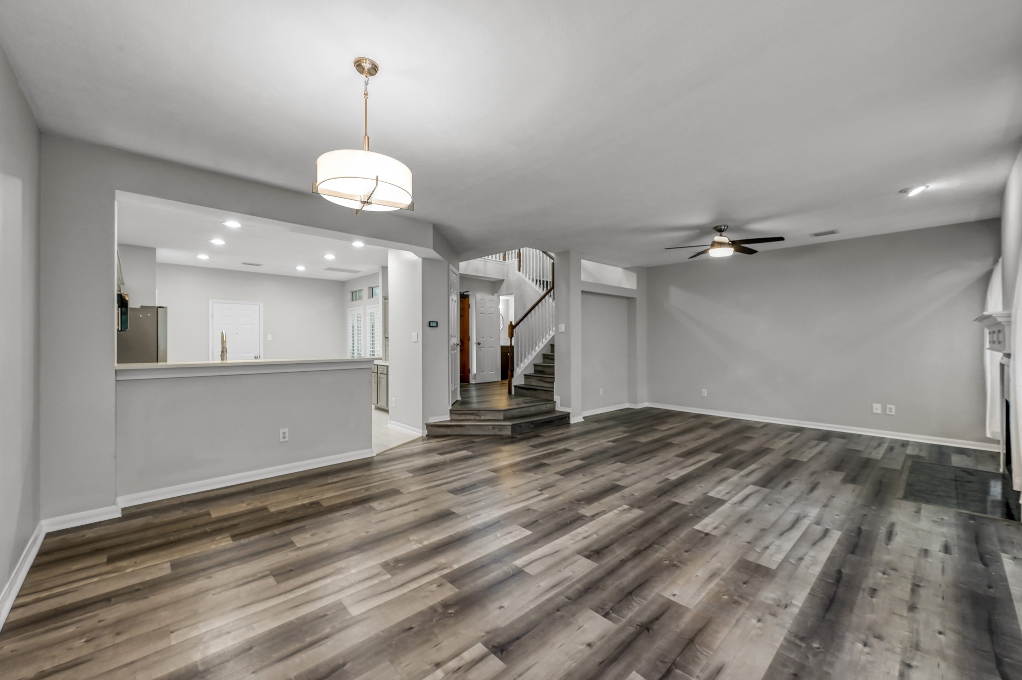 23 Alderon Woods Place Spring, TX 77382 - Photo 12 of 25 an empty room with wooden floor ceiling fan and kitchen view