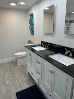 a bathroom with a granite countertop sink and a toilet