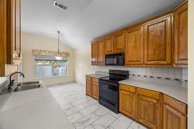 a kitchen with stainless steel appliances granite countertop a stove a sink and a microwave