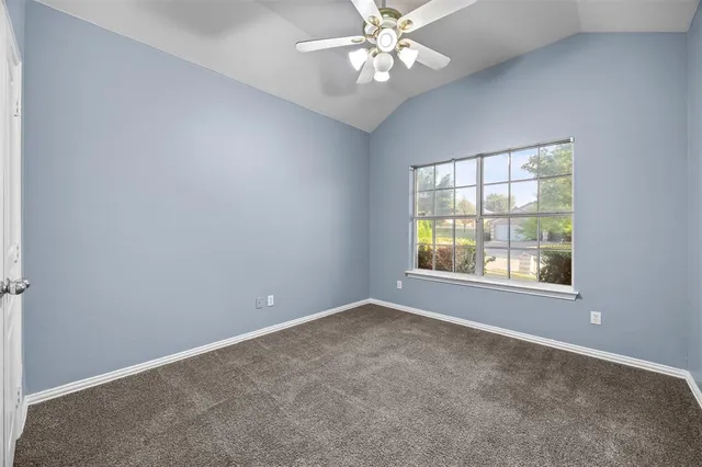 an empty room with windows and chandelier fan