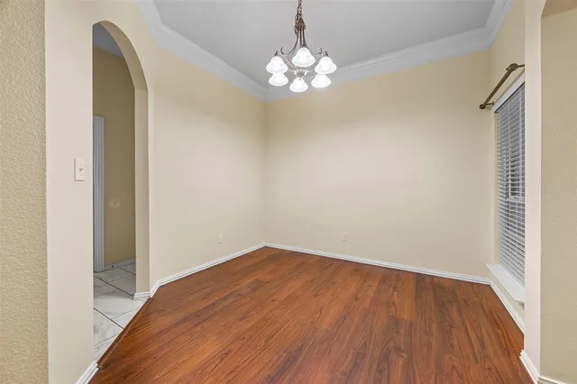 a view of a hallway with wooden floor and a chandelier