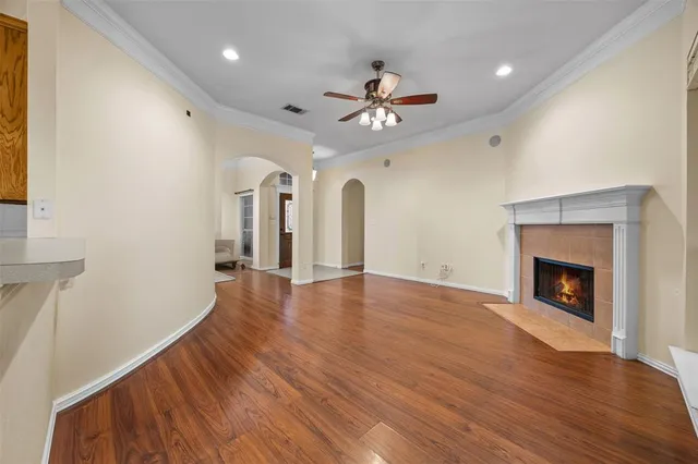 a view of an empty room with wooden floor and a fireplace