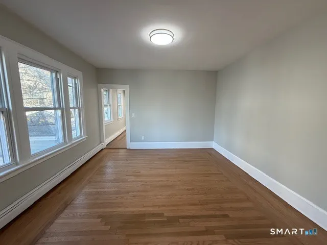 a view of an empty room with wooden floor and a window