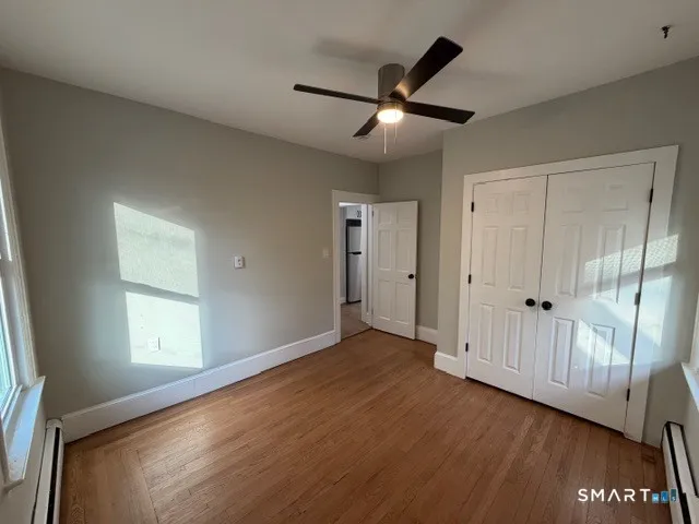 an empty room with wooden floor cabinet and windows