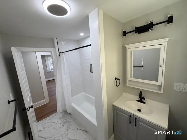 a bathroom with a sink a mirror toilet and shower