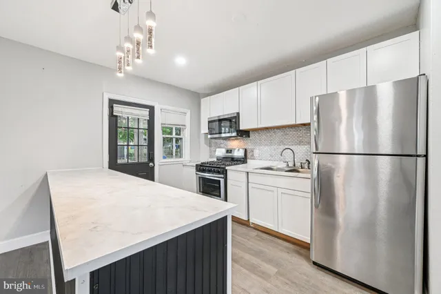 a kitchen with stainless steel appliances granite countertop a refrigerator a stove a sink dishwasher a refrigerator white cabinets and wooden floor