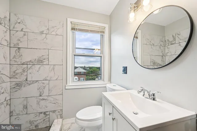 a bathroom with a sink a mirror a toilet and a window