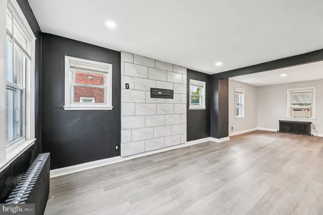 a view of an empty room with window and wooden floor