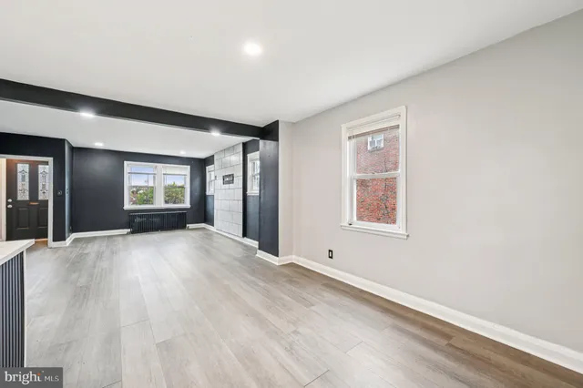 a view of an empty room with window and wooden floor