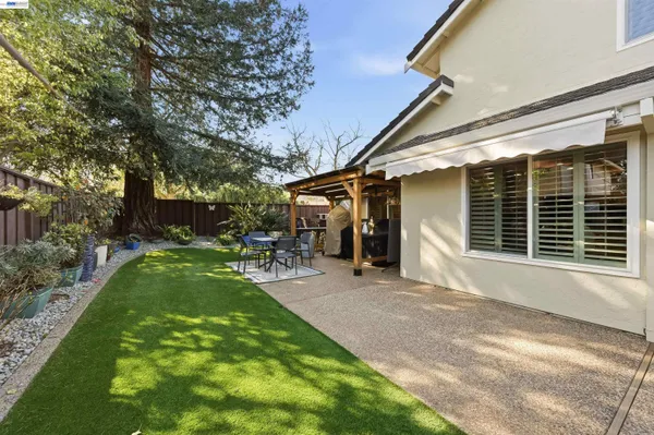 a view of a patio with table and chairs with plants and wooden fence