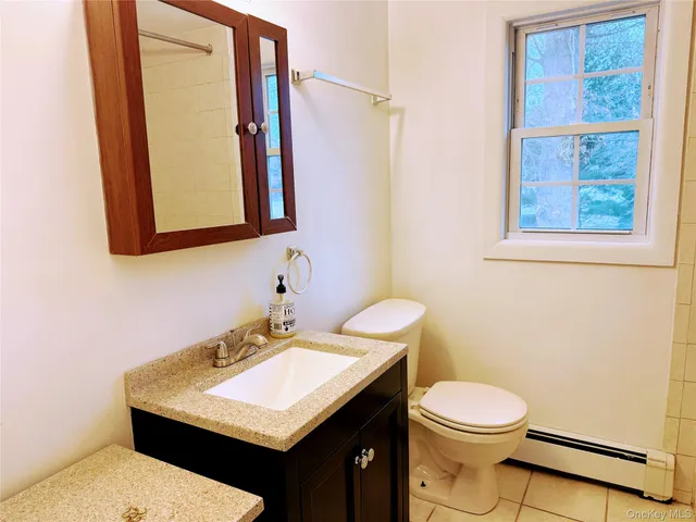 a bathroom with a sink a toilet a mirror and a window