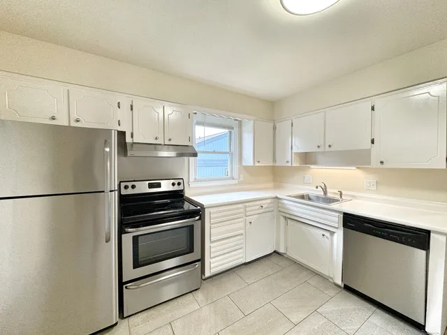 a kitchen with white cabinets and white appliances