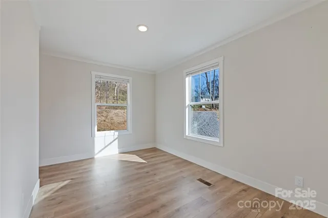 an empty room with wooden floor and windows