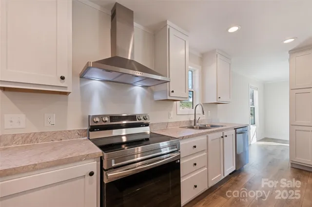 a kitchen with stainless steel appliances a stove and white cabinets