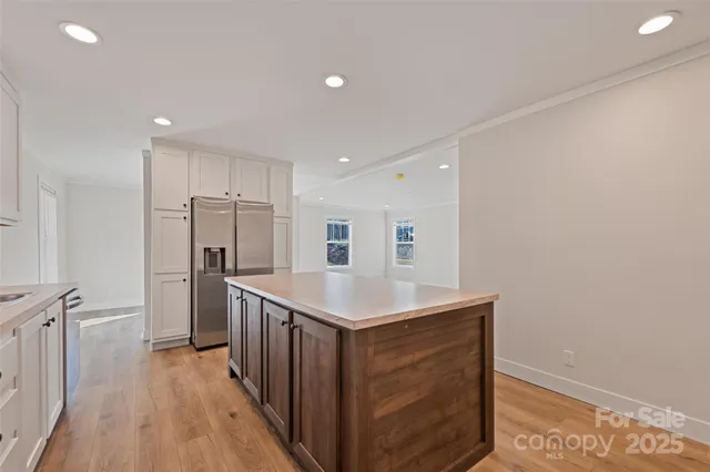 a kitchen with stainless steel appliances granite countertop a refrigerator a sink and wooden floor