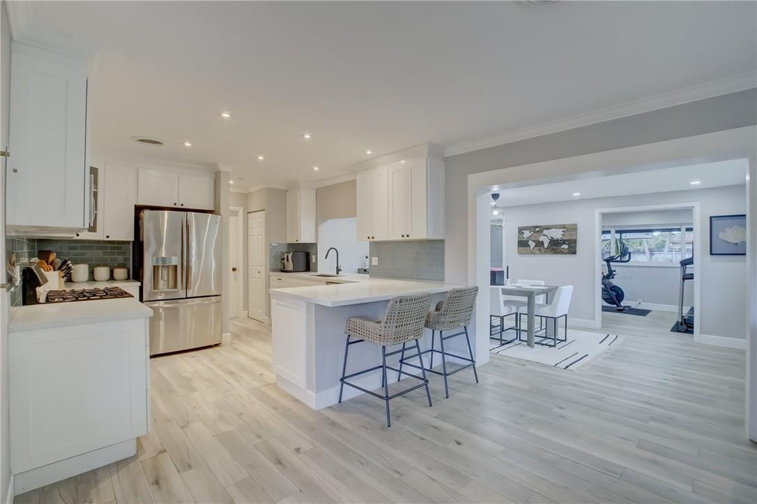4117 McKinley Street Hollywood, FL 33021 - Photo 11 of 52 a kitchen with stainless steel appliances a refrigerator a stove a sink dishwasher and a dining table with wooden floor
