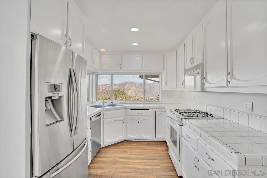 12040 Rocoso Road Lakeside, CA 92040 - Photo 13 of 56 a kitchen with white cabinets and stainless steel appliances